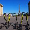 E-Tretroller zum Mieten stehen auf der Place du Trocadero in Paris, im Hintergrund ist der Eiffelturm zu sehen.