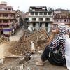 In Kathmandu beobachtet eine Frau die Aufräumarbeiten an einem durch das Beben zerstörten Tempel.