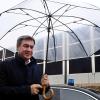 Notgedrungen mit Regenschirm auf dem Weg zur Photovoltaikwand zwischen Meitingen und Thierhaupten: Ministerpräsident Markus Söder.