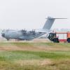 Ein Airbus-Militärtransporter A400M fährt an einem Einsatzfahrzeug der Flughafenfeuerwehr vorüber.