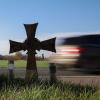 Ein Kreuz steht an einer Landstraße und erinnert an ein Unfallopfer.