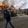 Ein Anwohner läuft an einem brennenden Haus in Cherson vorbei, das nach ukrainischen Angaben bei russischem Beschuss am orthodoxen Weihnachtsabend getroffen wurde.