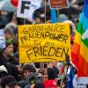 Ein Teilnehmer einer Demonstration für Verhandlungen mit Russland am Brandenburger Tor hält ein Plakat mit der Aufschrift «Sarah + Alice - Frauenpower für den Frieden».