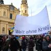 Demonstranten laufen mit Bannern mit der Aufschrift "Welt ohne Krieg" über den Odeonsplatz. Die 59. Münchner Sicherheitskonferenz (MSC) findet vom 17. bis zum 19. Februar 2023 im Hotel Bayerischer Hof in München statt. 