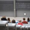 Studierende mit Mund- und Nasenmaske sitzen in einem Hörsaal.