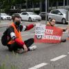 Drei Klimaaktivisten der Gruppe "Aufstand der letzten Generation"  blockieren eine Straße in Stuttgart.  

