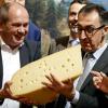 Cem Özdemir (Bündnis 90/Die Grünen) hält beim Eröffnungsrundgang über das Messegelände der Grünen Woche am Stand der Schweiz ein großes Stück Käse in Händen. 