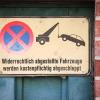 Ein Schild an einem Garagentor weist darauf hin, das widerrechtlich abgestellte Fahrzeuge abgeschleppt werden - und das kann teuer werden.