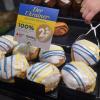 Eine Mitarbeiterin greift mit einer Zange einen Ukrainer-Spenden-Berliner in der Kieler Bäckerei Günther.