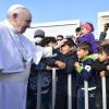 Papst Franziskus legt einem Jungen im Flüchtlingslager auf der Insel Lesbos die Hand auf den Kopf.