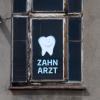 Zahnarzt steht an einem Fenster eines Hauses geschrieben, in dem sich eine Zahnarztpraxis befindet.