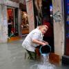 Eine Frau schöpft mit einem Eimer Wasser aus einem überfluteten Geschäft. In Venedig wurde ein Hochwasser von 150 Zentimetern erwartet - so viel wie seit zehn Jahren nicht mehr.