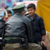Ein Junge unterhält sich, während er auf seinen Weitertransport in die diversen Erstaufnahmeeinrichtungen wartet, mit einem Polizisten.