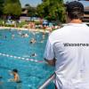 Ein Mann von der Wasserwacht steht während der Auftaktveranstaltung zur Kampagne "Bayern schwimmt 2023" oberhalb den Schwimmbecken.