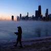 Eine Frau geht vor der Skyline von Chicago am Ufer des Michigansees entlang. 