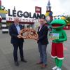 Axel Egermann, Geschäftsführer der RMG und Landkreismaskottchen Kalle Kammel gratulieren Martin Kring zum 15. Geburtstag von Legoland Deutschland. 	 	