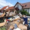 Vor einem Wohnhaus in Baiersdorf (Mittelfranken) liegt vom Wasser zerstörter Hausrat.