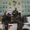 Vor dem Abschied: Mitglieder der kurdischen Sicherheitskräfte stehen in Manbidsch auf ihrem Fahrzeug vor einem Riesenposter mit Porträts von Kämpfern, die im Kampf gegen den Islamischen Staat getötet wurden. 	 	