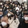 Menschen mit Mund-Nasen-Schutz gehen während der Hauptverkehrszeit durch eine U-Bahn-Station in Peking.