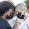 Zwei junge Frauen mit Mund-Nase-Schutz in einem innigen Moment. Am Montag beginnt die internationale Woche gegen Rassismus. 	