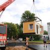 In Ursberg entsteht eine neue Kleinsthaus-Siedlung: Hier wird die erste Hälfte eines Holzhauses, das im Dominikus-Ringeisen-Werk gebaut wurde, auf das vorbereitete Fundament gestellt.