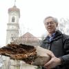 Der Dachstuhl der Pfarrkirche war in einem kritischen Zustand. Kirchenpfleger Johann Mayr zeigt ein Stück eines vermoderten Balkens, der ausgetauscht werden musste. 	
