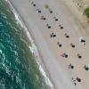 An einem Strand mit Blauer Flagge südlich von Athen stehen Sonnenschirme für Strandbesucher bereit.