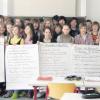 Das Foto zeigt die siebte Klasse mit ihrem Klassenlehrer Reinhard Feisthammel (2. v. l.) und Thomas Striebl (2. v. r.) mit den erarbeiteten Themen auf Plakaten im Klassenzimmer nach dem Besuch bei der Polizeiinspektion Aichach. 