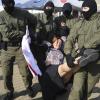 Polizisten tragen am Rande einer Demonstration in Minsk eine Frau weg.