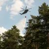 Die Feuerwehr wird von einem Hubschrauber mit Löschwasserbehälter unterstützt.