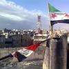 Ein undatierte Fotografie, die am 16. Februar von der Oppostition in Syrien veröffentlich wurde zeigt die Flagge der Syrieischen Revolutionäre (rechts) die anstatt der Nationalflagge über den Dächern der Protesthochburg Homs weht.