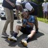 Mark Cavendish verzerrt das Gesicht vor Schmerz, während er auf der Straße sitzt und nach einem Sturz medizinische Hilfe erhält. 