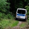 Ein Polizeiwagen fährt im Bereich der südlichen Landesgrenze von Berlin durch den Wald.