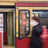 Eine Frau geht an einer S-Bahn vorbei.