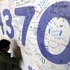 Ein Mann schreibt 2014 eine Nachricht an Passagiere des verschwundenen Fluges auf ein Banner am Flughafen von Kuala Lumpur.
