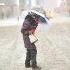 Eine Frau versucht sich in New York mit einem Regenschirm vor Schnee und Wind zu schützen.