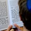Jüdischer Alltag in Deutschland: Ein Schüler der Joseph-Carlebach-Schule in Hamburg, der eine blaue Kippa trägt, schaut in ein Gebetbuch mit hebräischen Schriftzeichen. 