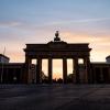 Die Wolken hinter dem Brandenburger Tor sind hell erleuchtet.