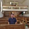 Kirchenpfleger Paul Kammerer hat es sich auf den in Eigenleistung renovierten Kirchenbänken bequem gemacht.