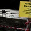 Schaulustige sitzen auf einem Steg am abgesperrtem Ufer des abgelassenen Oggenrieder Weiher in Irsee bei Kaufbeuren. In dem Badesee wird eine Alligator-Schildkröte vermutet.