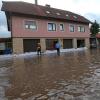 Feuerwehrleute arbeiten nach einem Starkregen in Untersteinbach in Unterfranken auf einer überfluteten Straße. Zahlreiche Straßen und Keller waren überschwemmt worden.