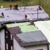 Feuerwehrleute decken in Bad Bayersoien beschädigte Dächer mit großen Planen ab.