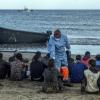 Migranten aus Marokko kommen mit einem Holzboot an der Küste Gran Canarias an und lassen Temperatur messen. Statt Urlaubern mit Rollkoffern kommen dieses Jahr 19.000 Flüchtlinge, was die Kanarischen Inseln überfordert.