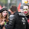 Zwei Teilnehmer einer Mai-Demonstration gegen Rassismus haben sich in Chemnitz als Clowns geschminkt und unterhalten sich mit einem Polizisten in Einsatzkleidung.