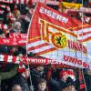 Fans von Union Berlin feuern ihr Team mit Schals und Fahnen an.