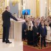 Russlands Präsident Wladimir Putin (li.) spricht bei seiner Amtseinführung im Kreml, während er seine Hand auf die Verfassung legt. Altkanzler Gerhard Schröder steht bei den Gästen.