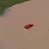 Dieses Videostandbild zeigt ein Auto, das auf einer überfluteten Rasenfläche steht.