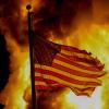 Eine ausgefranste US-Flagge weht vor den Flammen eines angezündeten Gebäudes. Die Gewalt ist nach den tödlichen Schüssen auf Jacob Blake bei einem Polizeieinsatz erneut eskaliert.