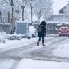 Eine Frau geht auf einer mit Schnee bedeckten Straße.