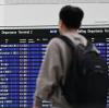 Ein Passagier steht im Münchner Flughafen vor der Anzeigentafel.